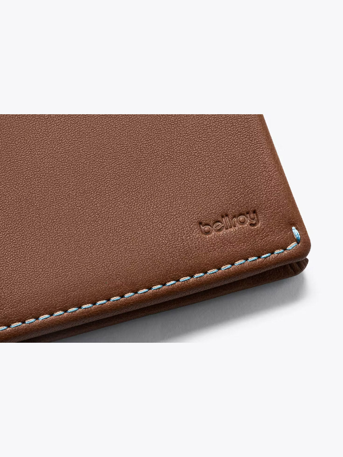 Close-up of the Bellroy Slim Sleeve Wallet’s brown leather corner with blue stitching and embossed branding, highlighting its slim, pocket-friendly design.