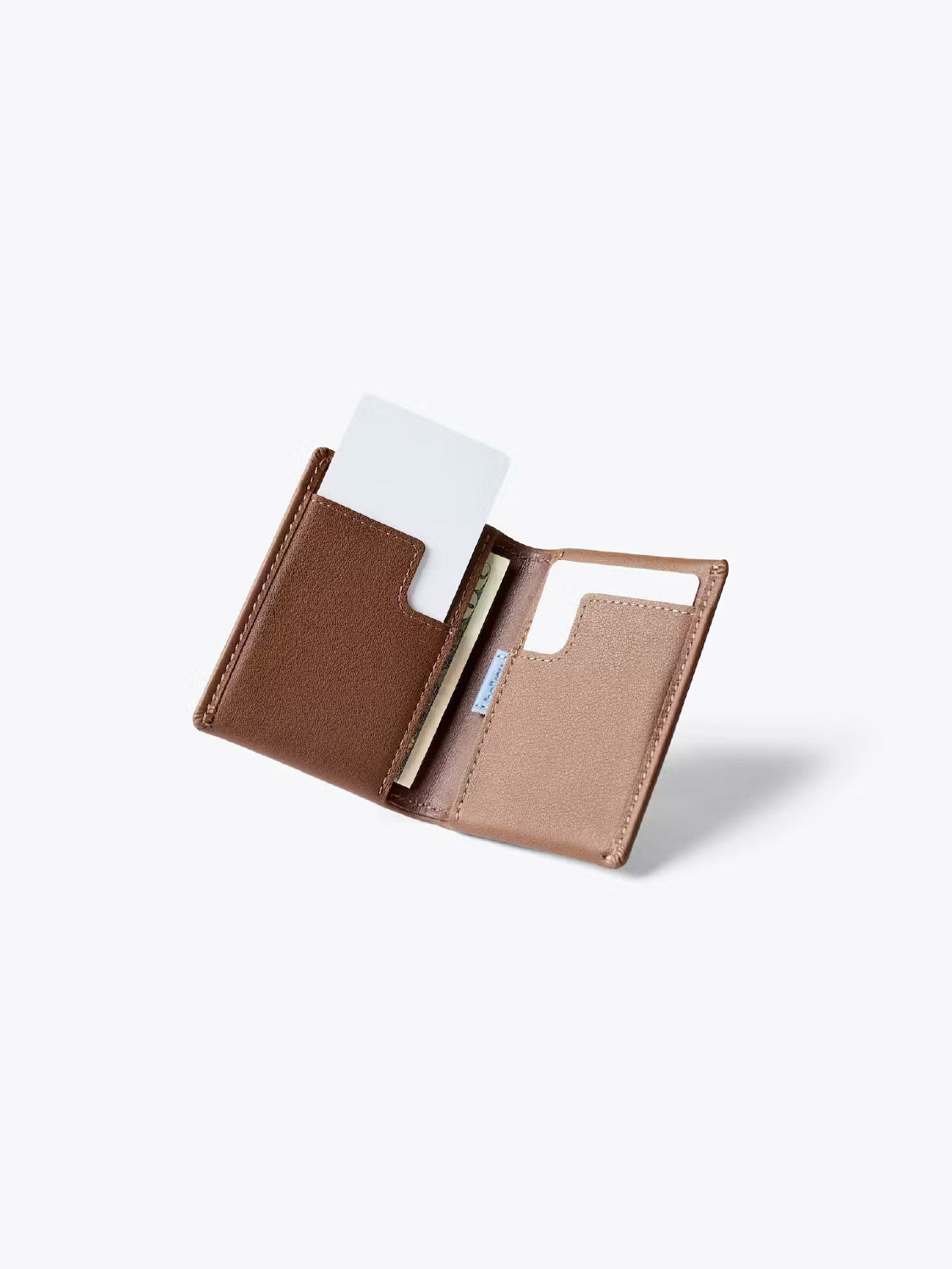The Bellroy Slim Sleeve Wallet, a compact brown bi-fold leather design, is shown open with card and cash slots visible, set against a plain light background.