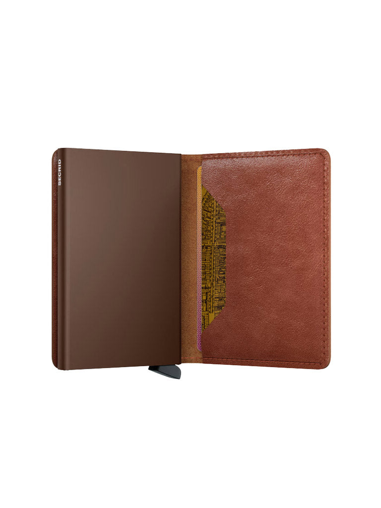 The Secrid Slimwallet Vintage Leather by Secrid is shown open on a white background, with a closed notebook on the left and a pocket holding a yellow patterned card and RFID/NFC security on the right.