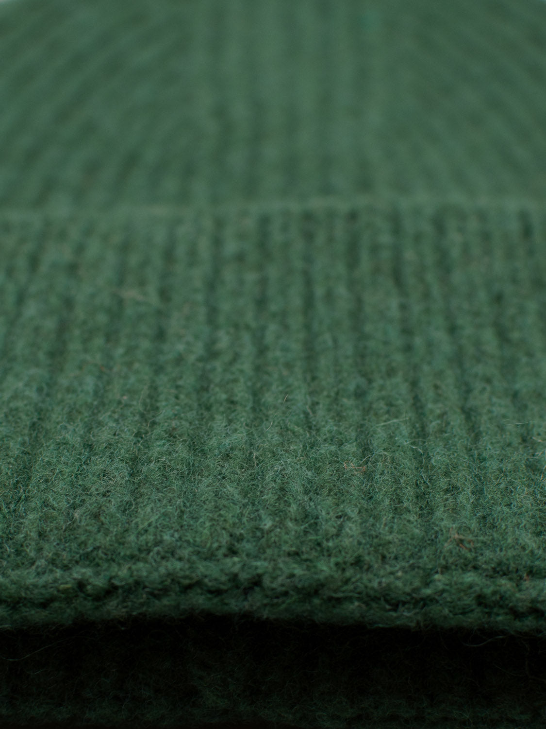 Close-up of Telluride Wool Beanie by ID Menswear in green, highlighting its detailed ribbed texture. The image showcases the beanies soft and warm appearance, offering natural insulation and suggesting a comfortable fit for chilly days.