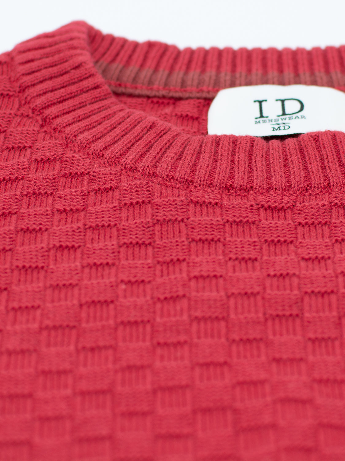Close-up of the Turku Cotton Sweater in red, featuring a stylish waffle-knit pattern. The visible ID Menswear tag confirms its a medium-sized, regular fit sweater with a ribbed collar that combines comfort and style.