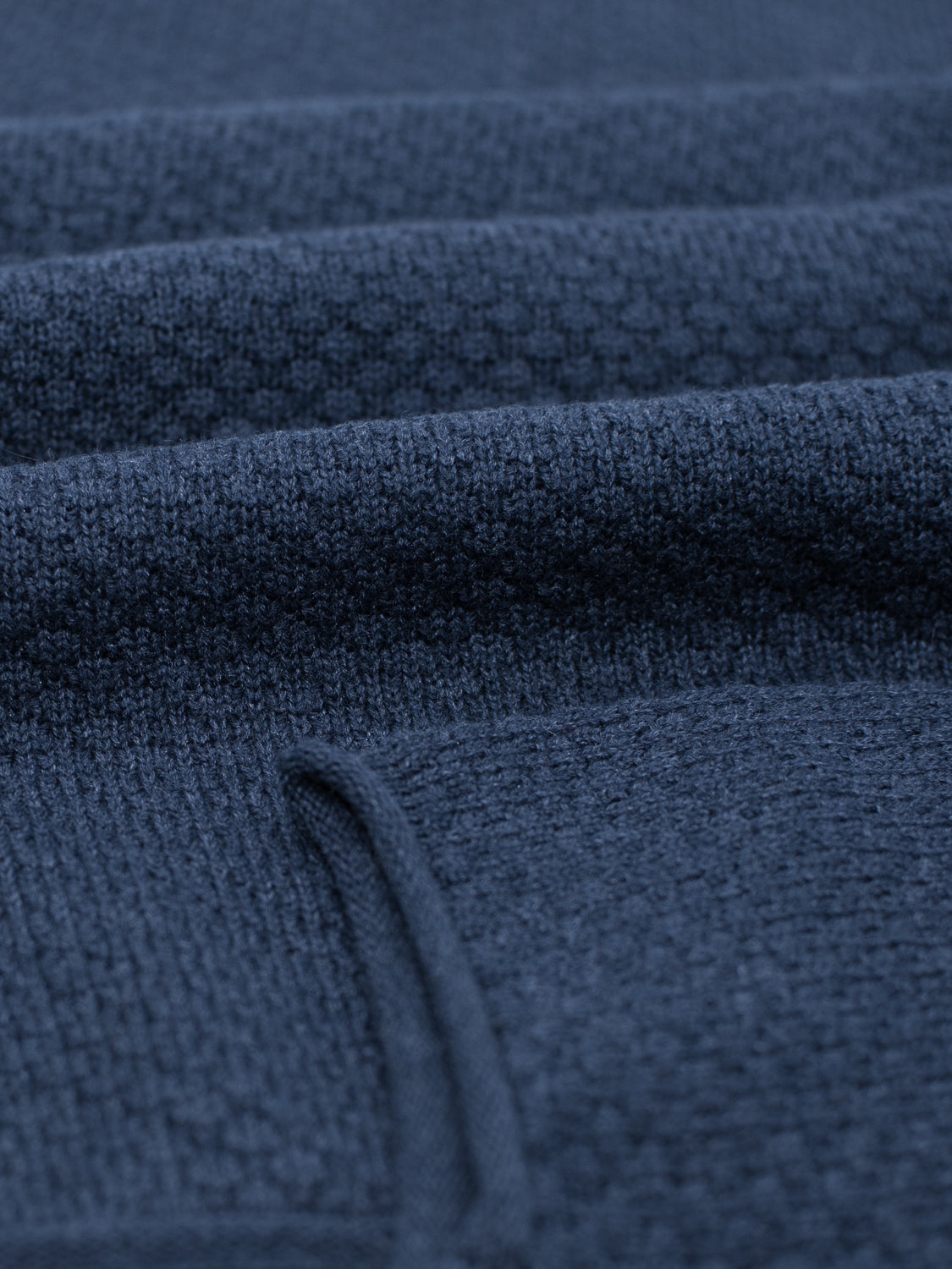 Close-up of folded dark blue knit fabric with visible texture and stitching, showcasing the exquisite detail of the ID Menswear Westside Rolled Crew Neck Sweater.