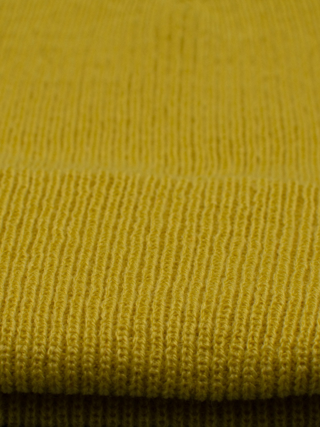 Close-up of the Yonker Ribbed Acrylic Beanie by ID Menswear, featuring yellow durable acrylic knit with a smooth texture and visible patterns, evoking a cozy feel.