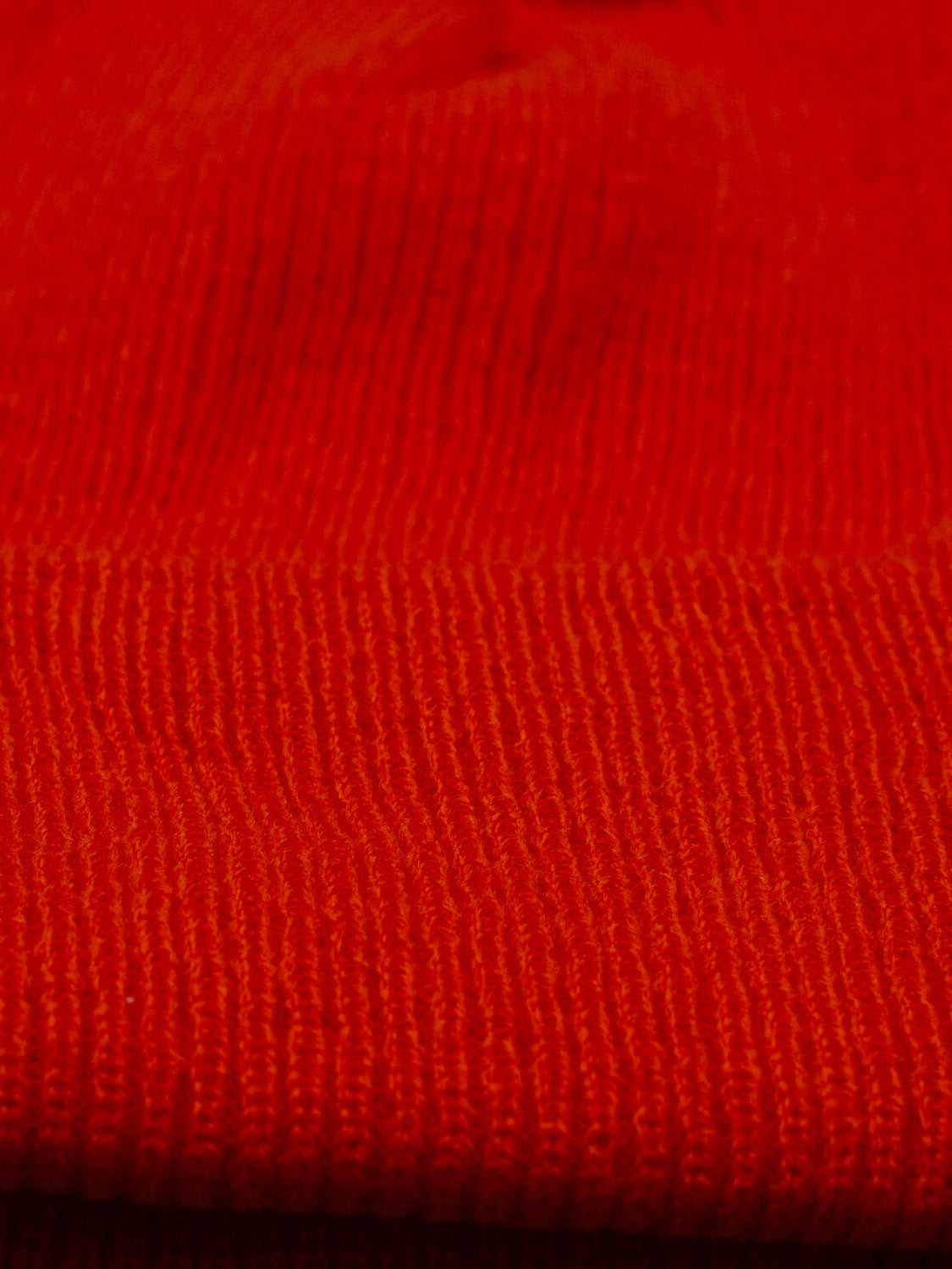 Close-up of the Yonker Ribbed Acrylic Beanie by ID Menswear, featuring its orange, rib-knit texture. Highlights include the fine stitches and pattern in the soft acrylic material, offering a subtle nod to classic fisherman style.