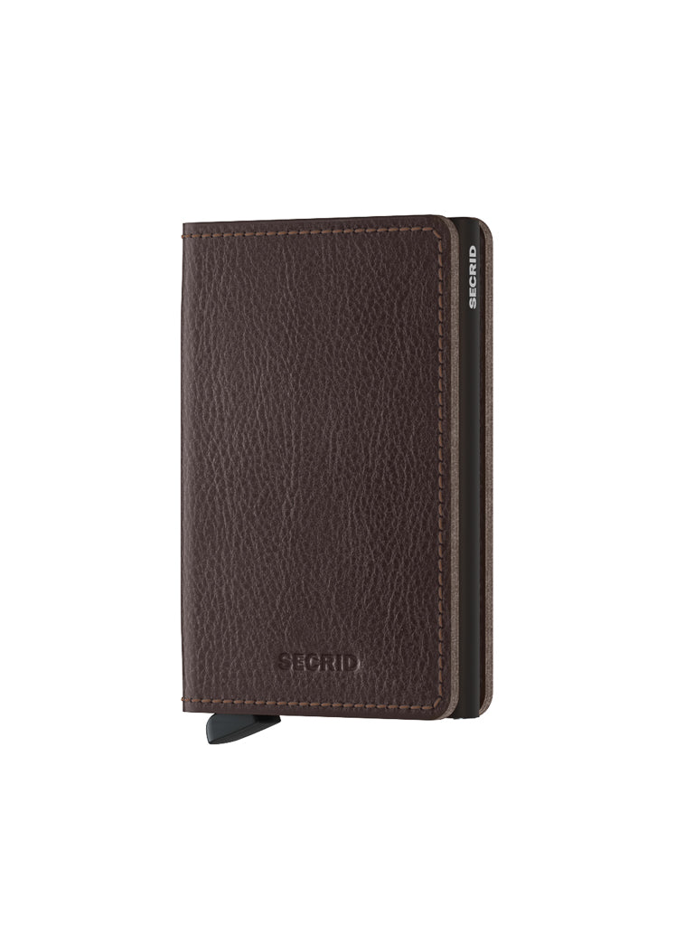 The Secrid Slimwallet Vegetable Tanned Leather features visible stitching, a textured finish, and an embossed SECRID logo on the front, partially revealing the metal cardholder inside. The wallet stands upright against a white background.