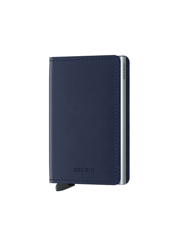 The Secrid Slimwallet Original is a closed, navy blue wallet with a sleek, minimalist design. Crafted from premium European leather, it has rounded edges, visible stitching, RFID protection, and a lever on the bottom left side.