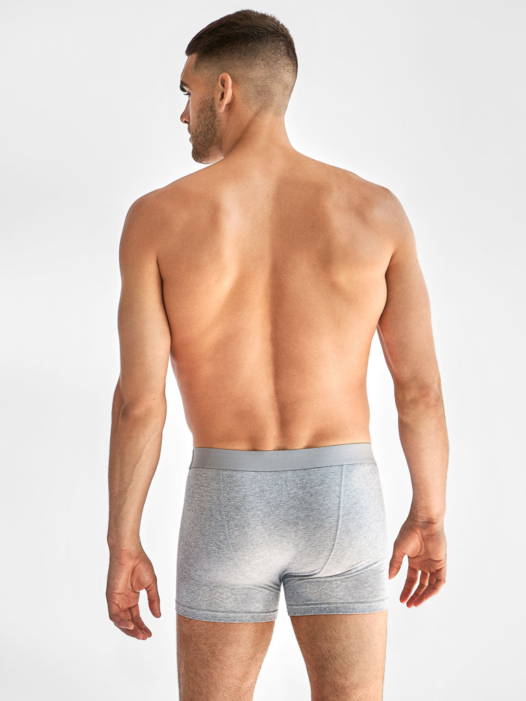 A man with short hair, seen from behind, wears Bread & Boxers gray boxer briefs with an elastic waistband against a plain white backdrop.