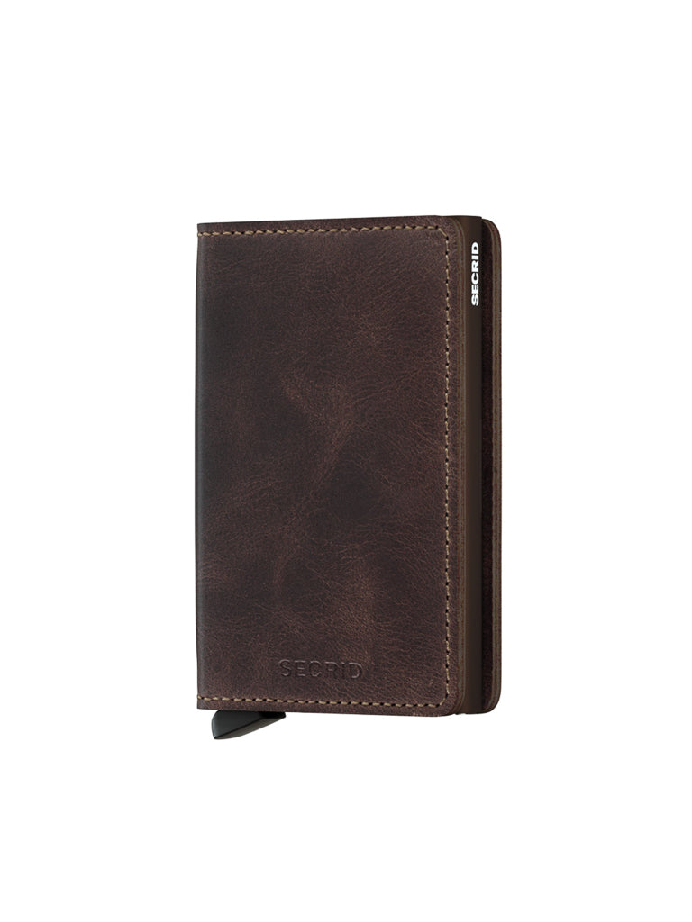 The Secrid Slimwallet Vintage Leather is a dark brown, slim wallet with visible stitching and a small metal tab on the bottom left, standing upright against a white background. "SECRID" is embossed on the front.
