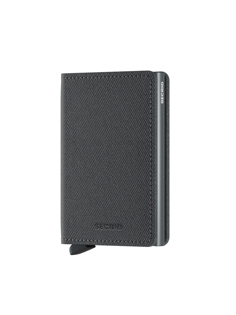 A Secrid Slimwallet Twist Twill Leather in black stands upright on a white background, featuring a textured surface, RFID protection, metal side, and a small tab at the bottom left for a sleek, slim design.