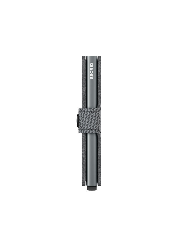 A top-down view of a gray pen held by a textured, woven gray loop attached to a Secrid Miniwallet Carbon Weave Pattern Leather case, isolated on white. The word SECRID is visible on the pen.