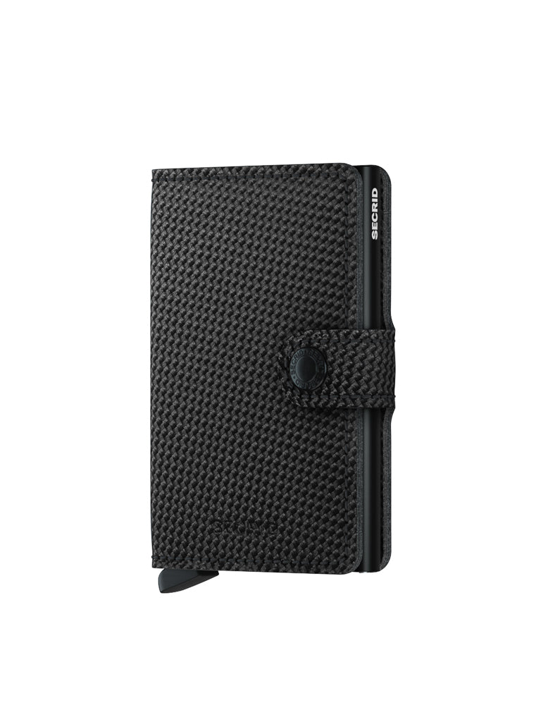 The Secrid Miniwallet Carbon Weave Pattern Leather, shown upright on a plain white background, features RFID protection, a snap button closure, and a bottom lever. The brand name "Secrid" appears in white on the upper right edge.