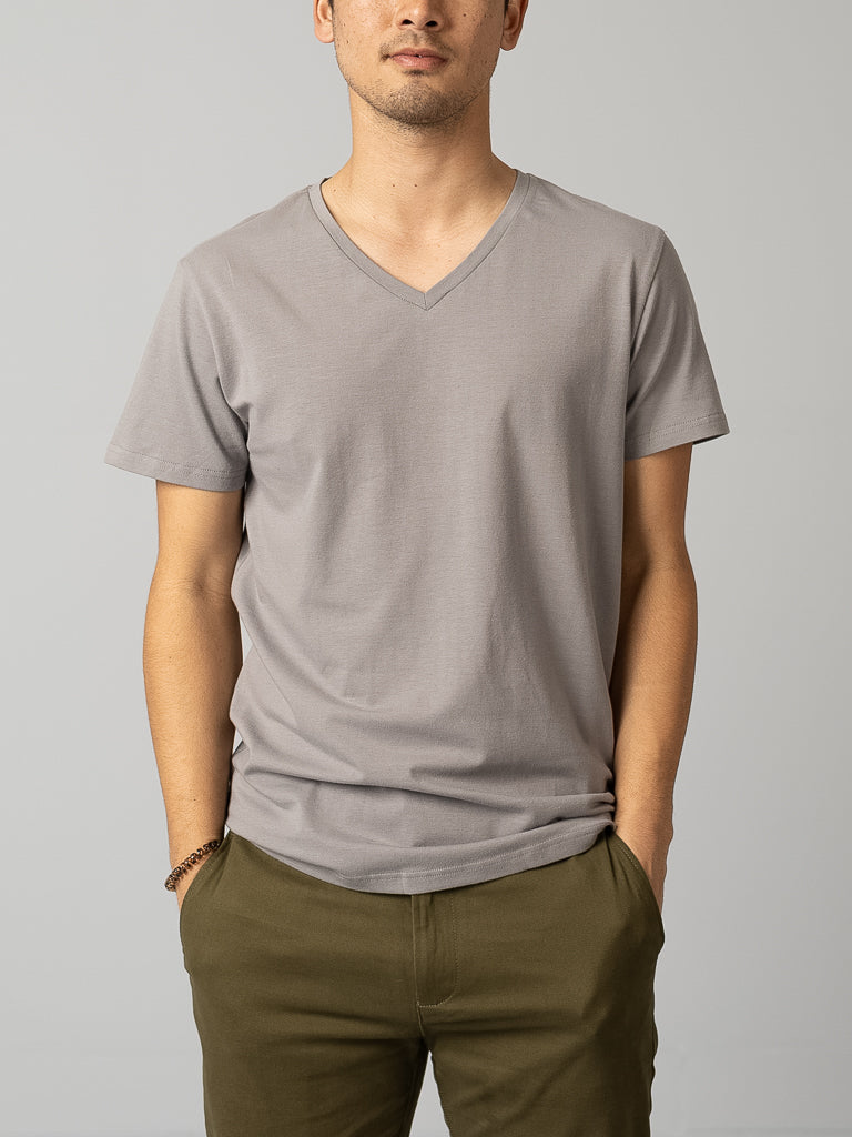 Wearing ID Menswears Form V Neck Tee in gray and olive green pants, a person exudes effortless style for any casual occasion, standing against a plain background with hands in pockets.