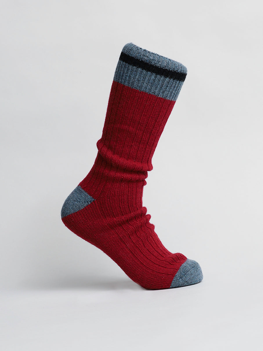 A single red Wool Blend Sock by ID Menswear, with gray toes and heel and a black and gray band near the top, stands upright against a plain white background. Ideal for cold weather or winter activities, it boasts a cozy ribbed texture.