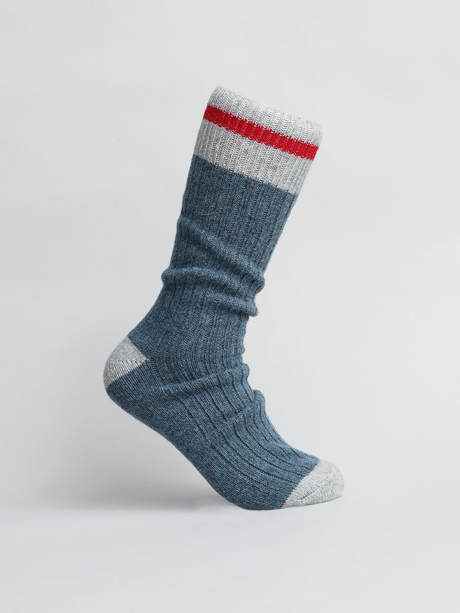 The product is a single ID Menswear Wool Blend Sock, featuring ribbed blue wool with gray heel and toe sections. It includes a white cuff with a red stripe, perfect for winter activities and staying warm in cold weather. Displayed on a plain white background.