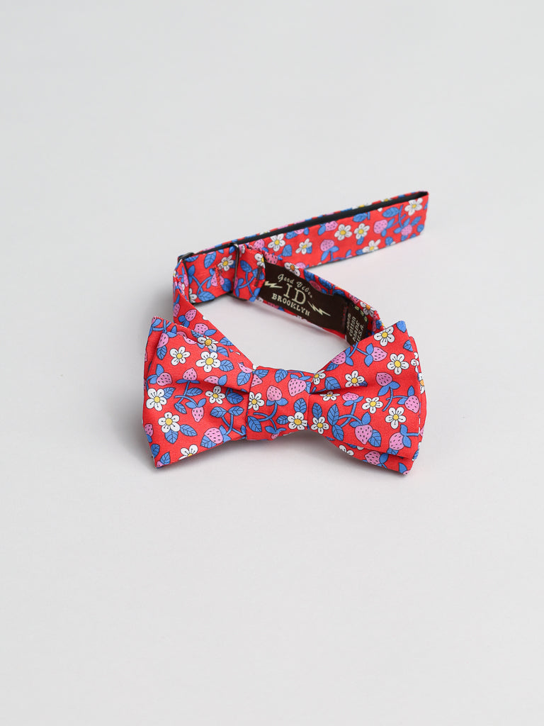 Handmade in Brooklyn by ID Menswear, the ID Liberty of London Tana Lawn™ Strawberries Cotton Bowtie presents a floral pattern with delicate white, pink, and blue flowers on Tana Lawn cotton. It is elegantly fastened and displayed against a light gray background.
