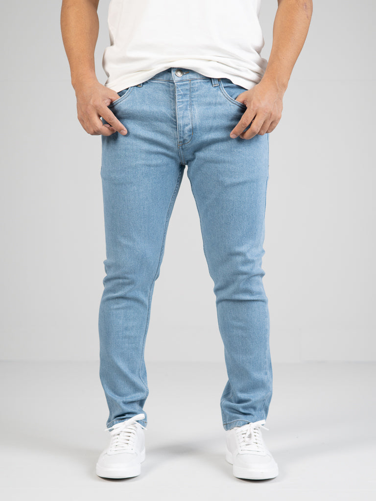 Someone wearing the Ganbaru Stretch Jean by ID Menswear with a white shirt and sneakers stands against a plain background, focusing on the jeans.