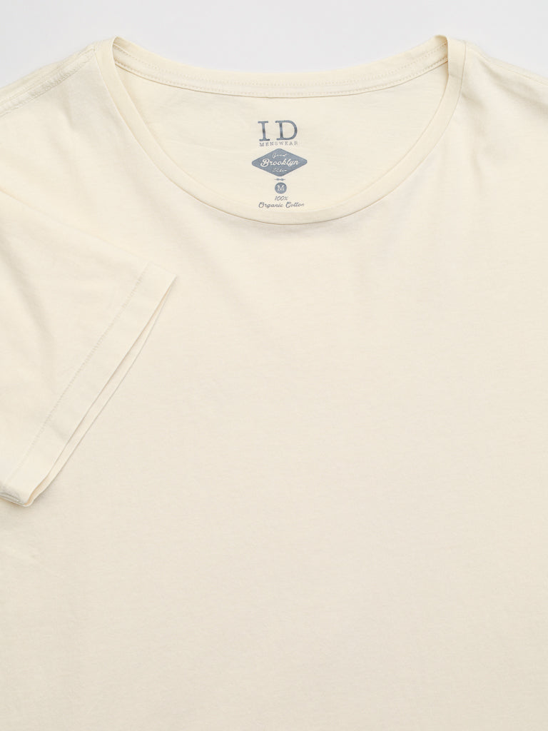 The Legacy Organic Cotton Tee by ID Menswear is a classic cream-colored T-shirt, made from 100% organic cotton. Laid flat, it highlights its neckline and I.D. Promotion label, offering a timeless and plain vintage look without extra design or text.