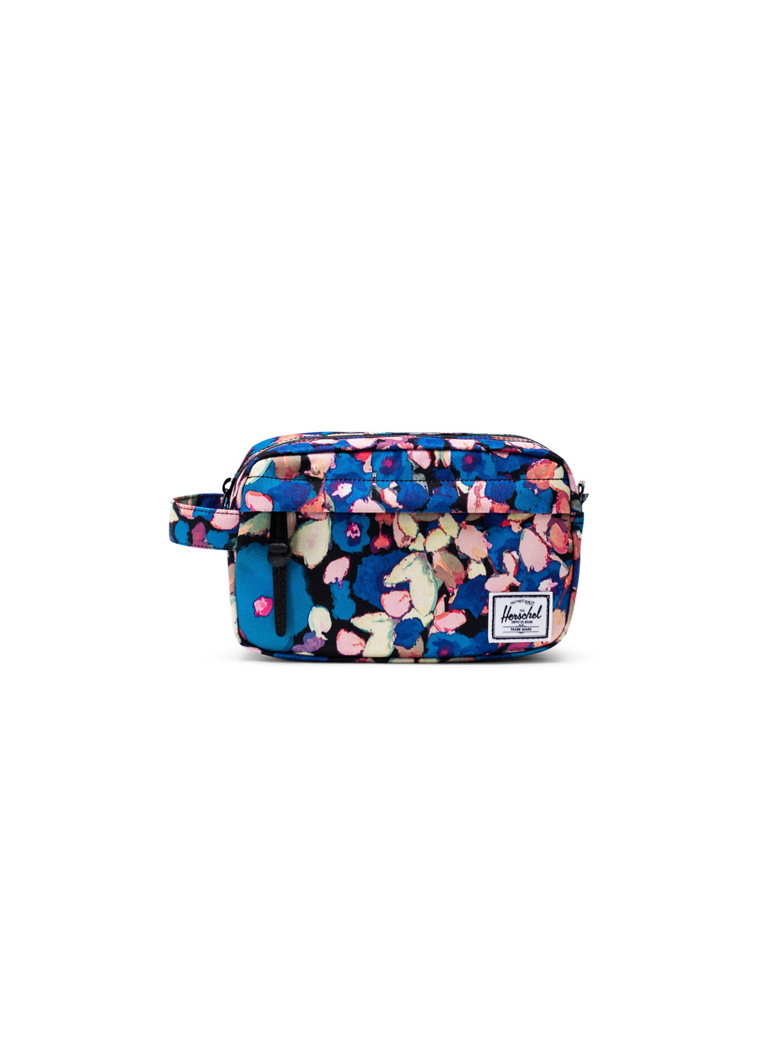 The Herschel Chapter Carry-On Travel Kit is a rectangular pouch with a blue, pink, and green floral pattern, a front pocket, waterproof zipper, wrist strap, and a white Herschel logo patch—ideal as a compact travel bag.