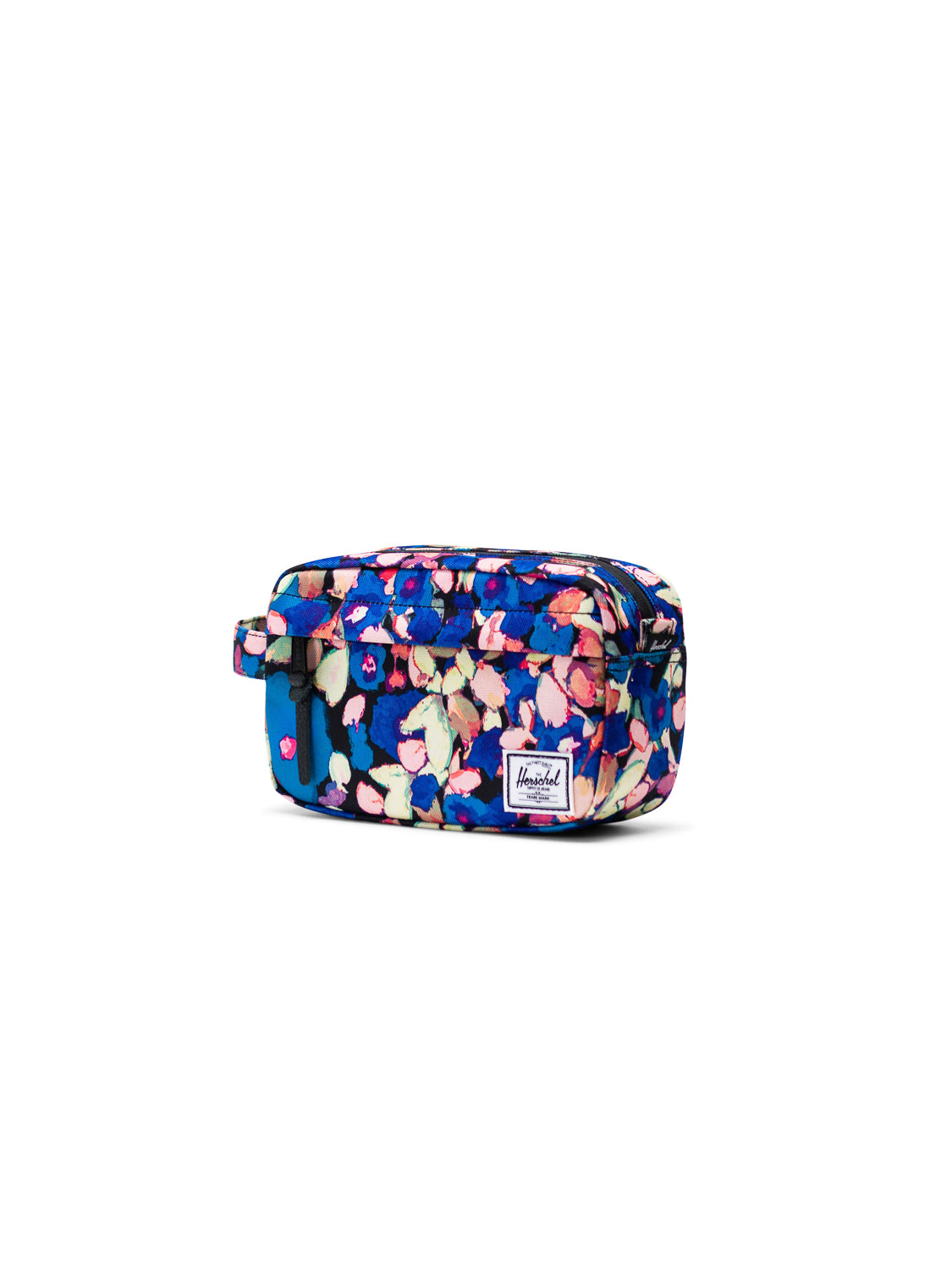 The Herschel Chapter Carry-On Travel Kit is a rectangular toiletry bag with a blue base and pink, white, and beige floral pattern. It features a side handle, waterproof zipper, and a front white Herschel label—ideal for travel.