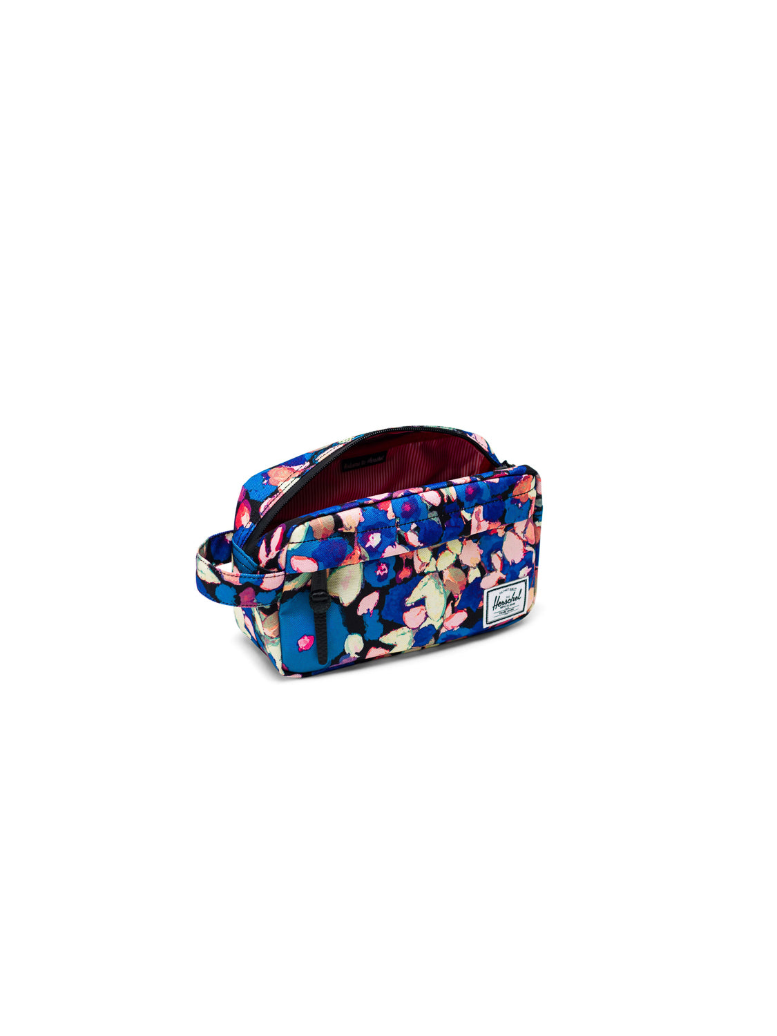 The Herschel Chapter Carry-On Travel Kit features a floral pattern, side handle, waterproof zipper, and a white front logo patch. Its interior is lined with red and white stripes for a stylish, practical travel solution.