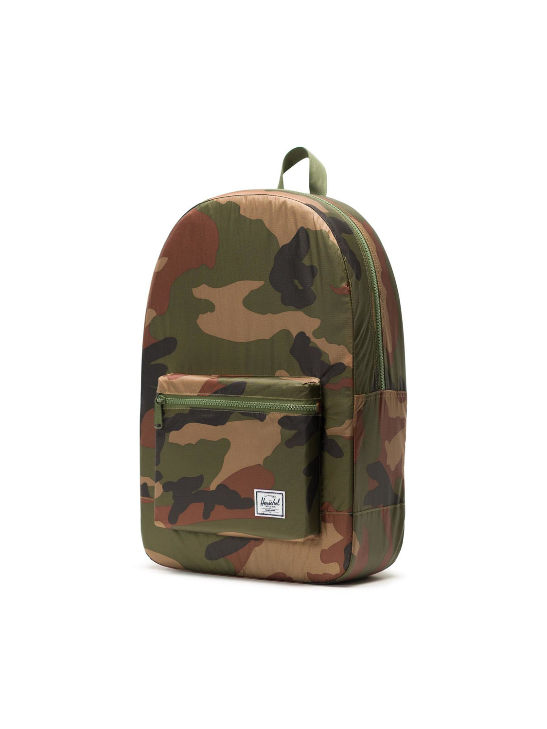 The Herschel Packable Daypack features a green, brown, and tan camouflage print, lightweight ripstop fabric, a front zip pocket, adjustable shoulder straps, and a small white logo patch, shown on a plain white background.