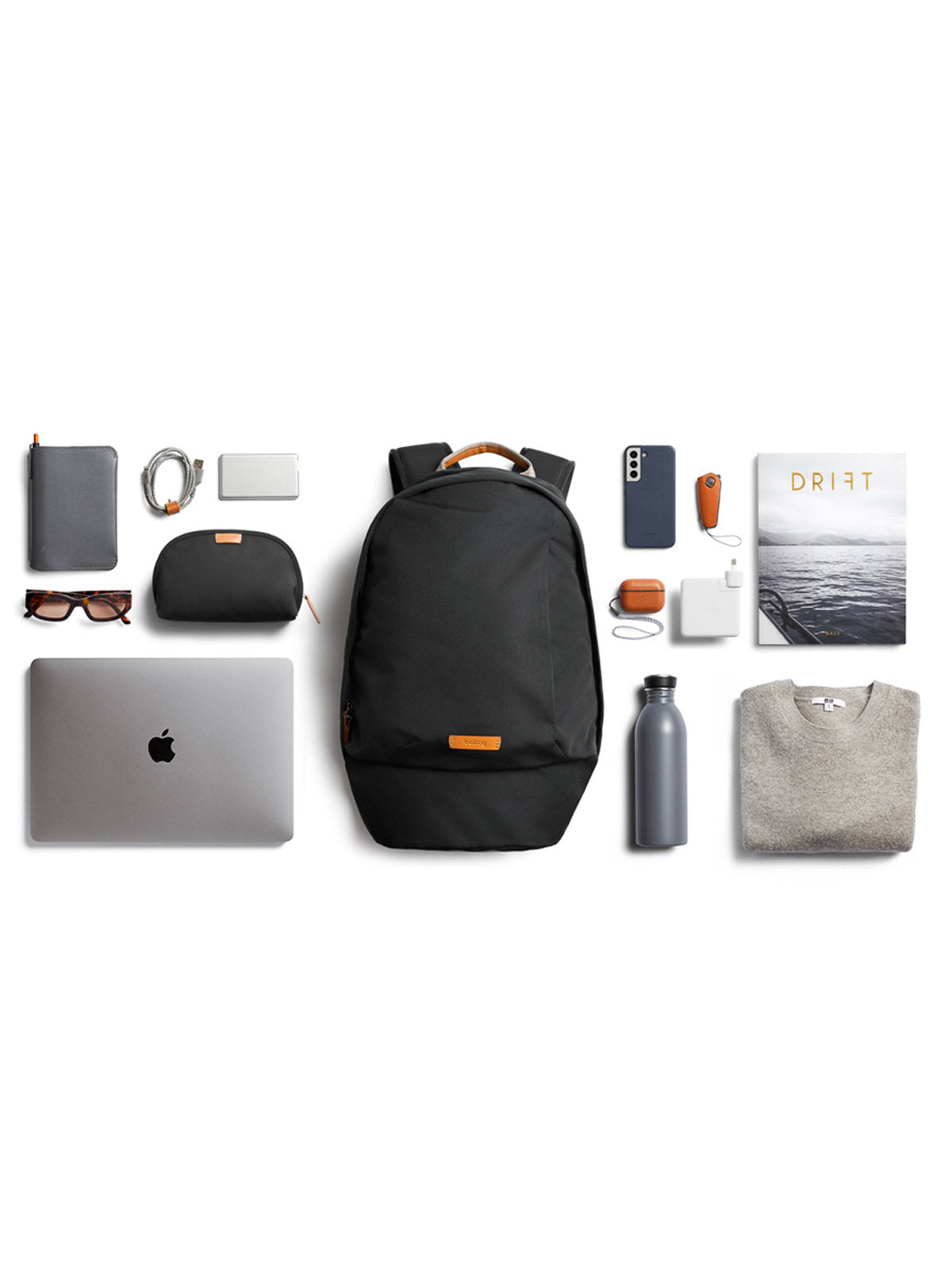A neatly arranged flat lay of travel essentials, including the Bellroy Classic Backpack - 20L made from recycled materials, a gray sweater, water bottle, laptop, sunglasses, headphones, power bank, charging cables, a book, and small pouches on a white background.