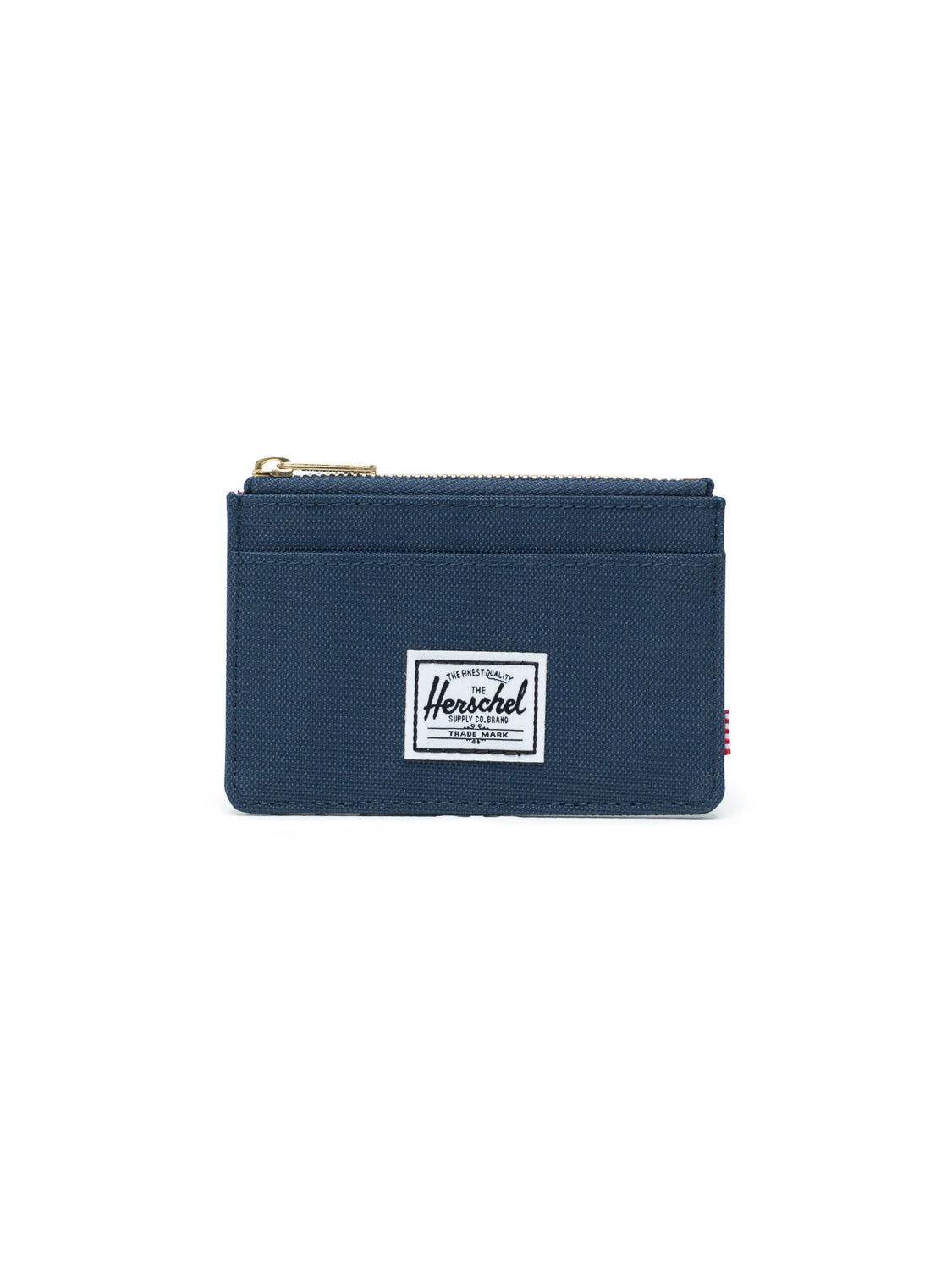 The Oscar Compact Wallet by Herschel is a navy blue fabric card holder with a top zipper, front pocket, and white rectangular Herschel label at the center. Shown against a white background.