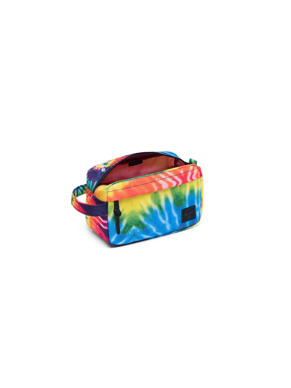 The Herschel Chapter Carry-On Travel Kit is a rectangular bag with a vibrant red, yellow, blue, and green tie-dye pattern, waterproof zipper closure, side handle, and front black label—ideal for travel essentials.