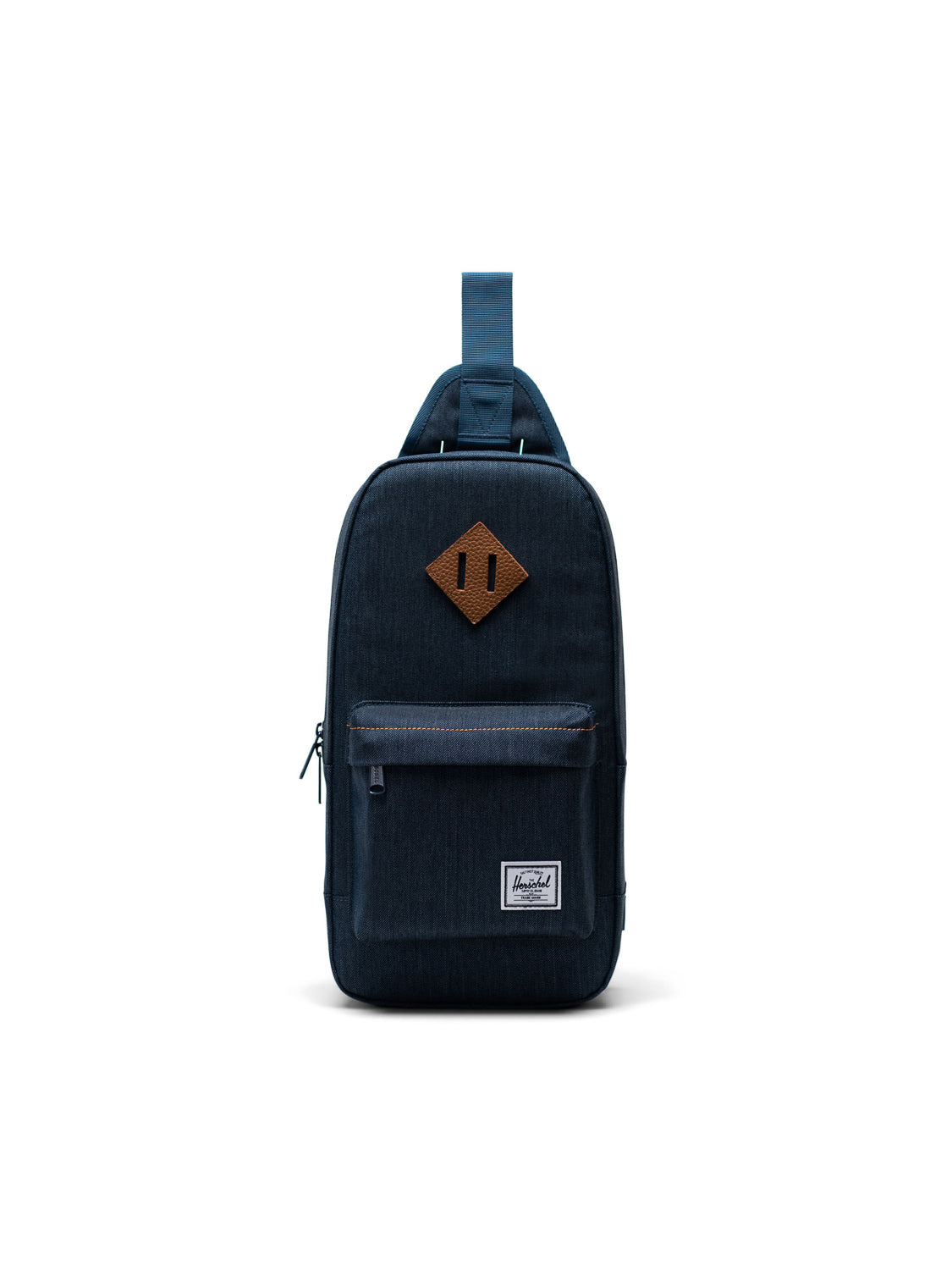 The Herschel Heritage Shoulder Bag is a navy blue crossbody backpack with a front zip pocket, a brown leather diamond patch, and a single top strap, shown on a plain white background.