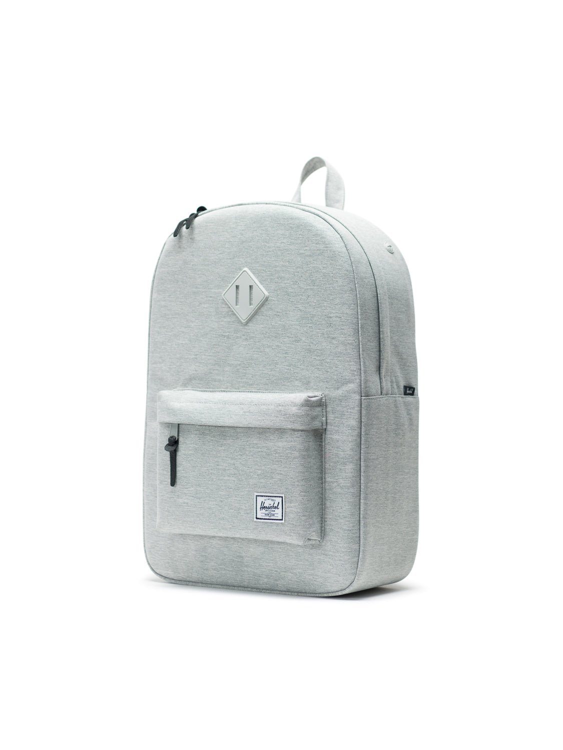The Herschel Heritage Backpack features a light gray minimalist design, a front zip pocket, padded laptop sleeve, top handle, black zipper pulls, and a rectangular logo patch on the lower front, inspired by classic mountaineering.