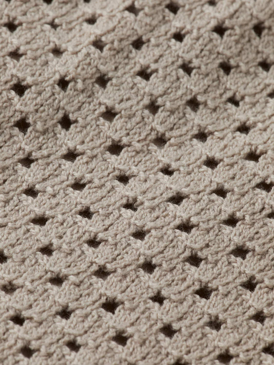Close-up of SCOTCH AND SODA's Crochet Knit Short 180344 SU25 in beige, featuring a textured, openwork pattern with diamond-shaped holes and raised stitches. Soft, slightly fuzzy yarn offers stylish comfort.