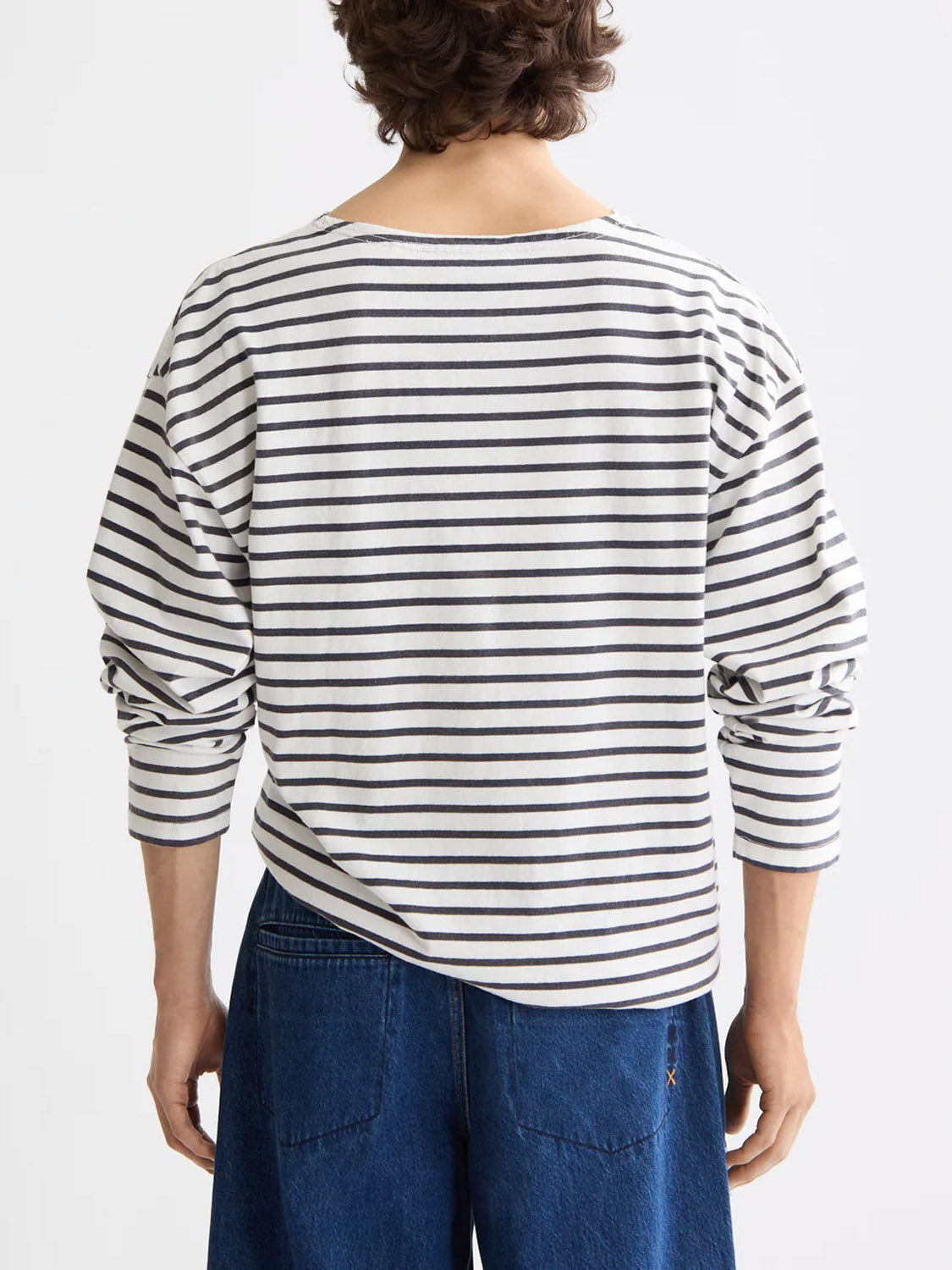 A person with wavy brown hair, seen from behind, wears the Scotch & Soda 180878 Denim Washed Long Sleeve Breton Tee against a plain white background.