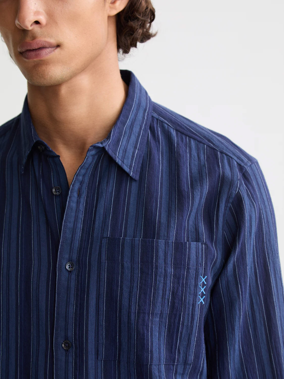 A person wearing the Scotch & Soda 181248 Textured Stripe Shirt in dark blue with vertical stripes and light blue stitching near the chest pocket, shown from shoulders to mid-torso against a plain background.