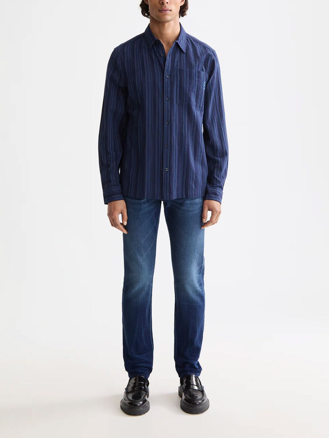 A person stands against a plain background wearing the Scotch & Soda 181248 Textured Stripe Shirt, paired with blue jeans and black shoes. Their arms are relaxed by their sides.