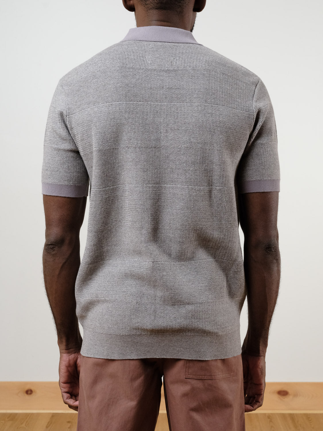 A person is shown from the back against a plain light background, wearing SCOTCH AND SODA's Knitted Tonal Striped Regular Polo in classic fit and mauve pants.