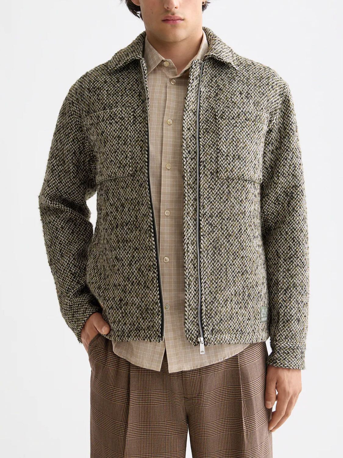 A person wears the Scotch & Soda 181609 Multicolored Tweed Overshirt over a beige button-up shirt and brown plaid trousers, standing against a plain white background.
