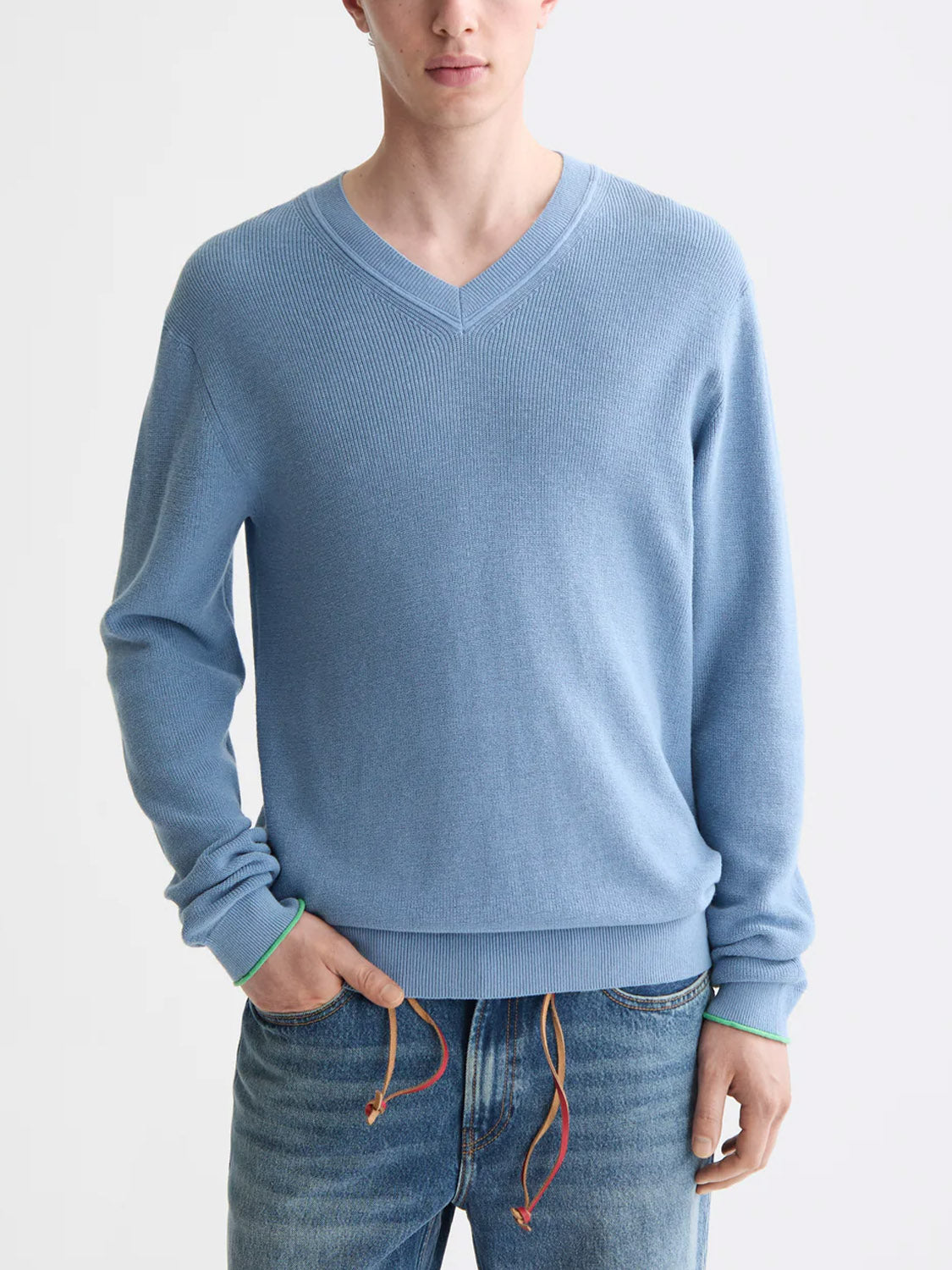 A person wears the Scotch &amp; Soda 181773 Cotton Linen V-Neck Pullover in light blue and blue jeans with adjustable waistband and orange drawstrings, standing against a plain light background. Only their upper body and one hand in pocket are visible.
