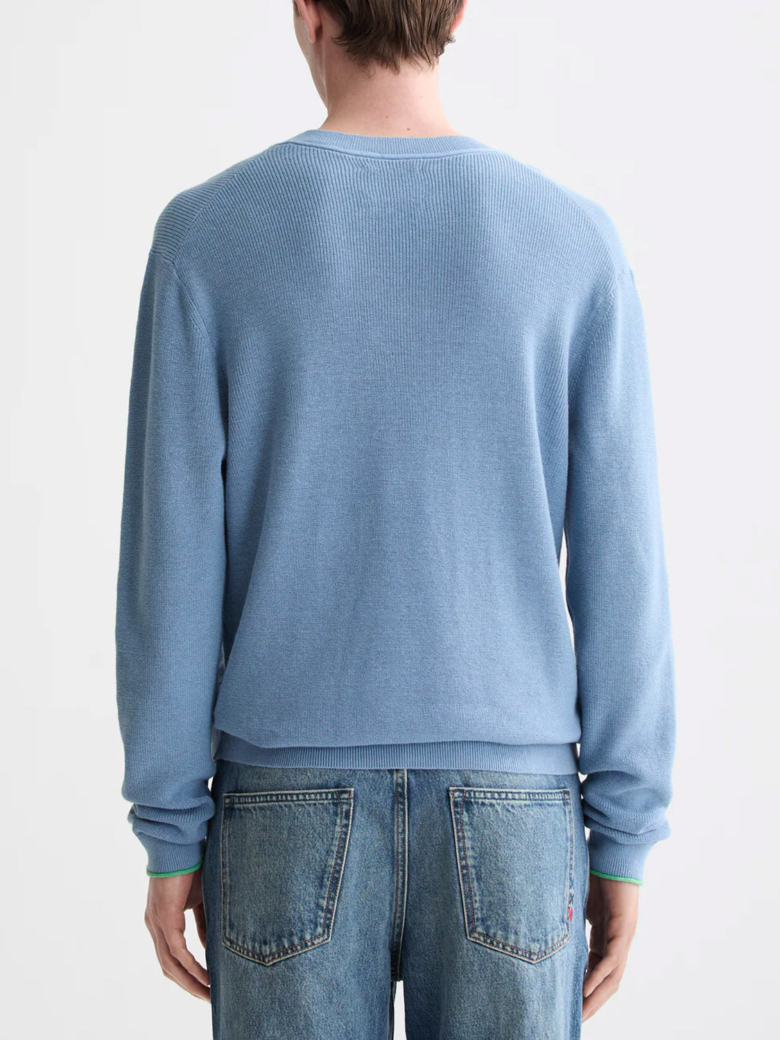 A person is shown from behind, wearing the Scotch & Soda 181773 Cotton Linen V-Neck Pullover in light blue, with mid-length blue jeans featuring an adjustable waistband, standing against a plain white background.