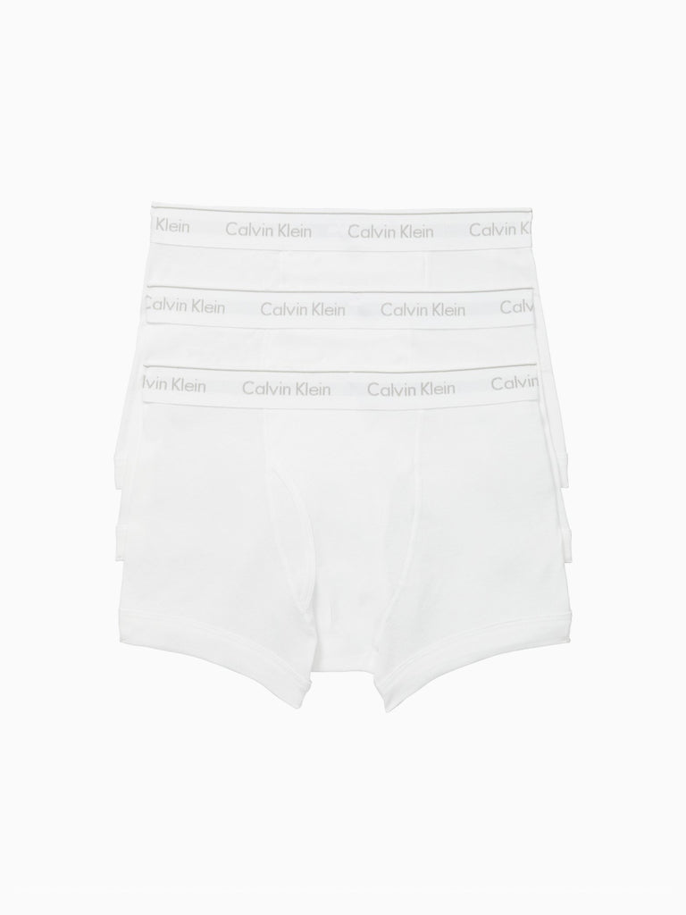 A 3-pack of Calvin Klein NB4002 Cotton Classic Fit Trunks is shown against a white background. Each white trunk features a light gray Calvin Klein logo on the elastic waistband, highlighting timeless men's underwear style.