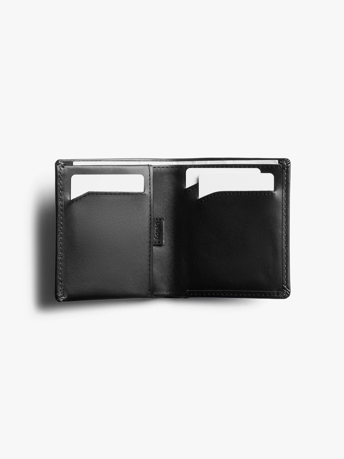 The Bellroy Note Sleeve Wallet, shown open on a white background, is a slim black leather wallet with RFID protection and two visible card slots holding white cards.