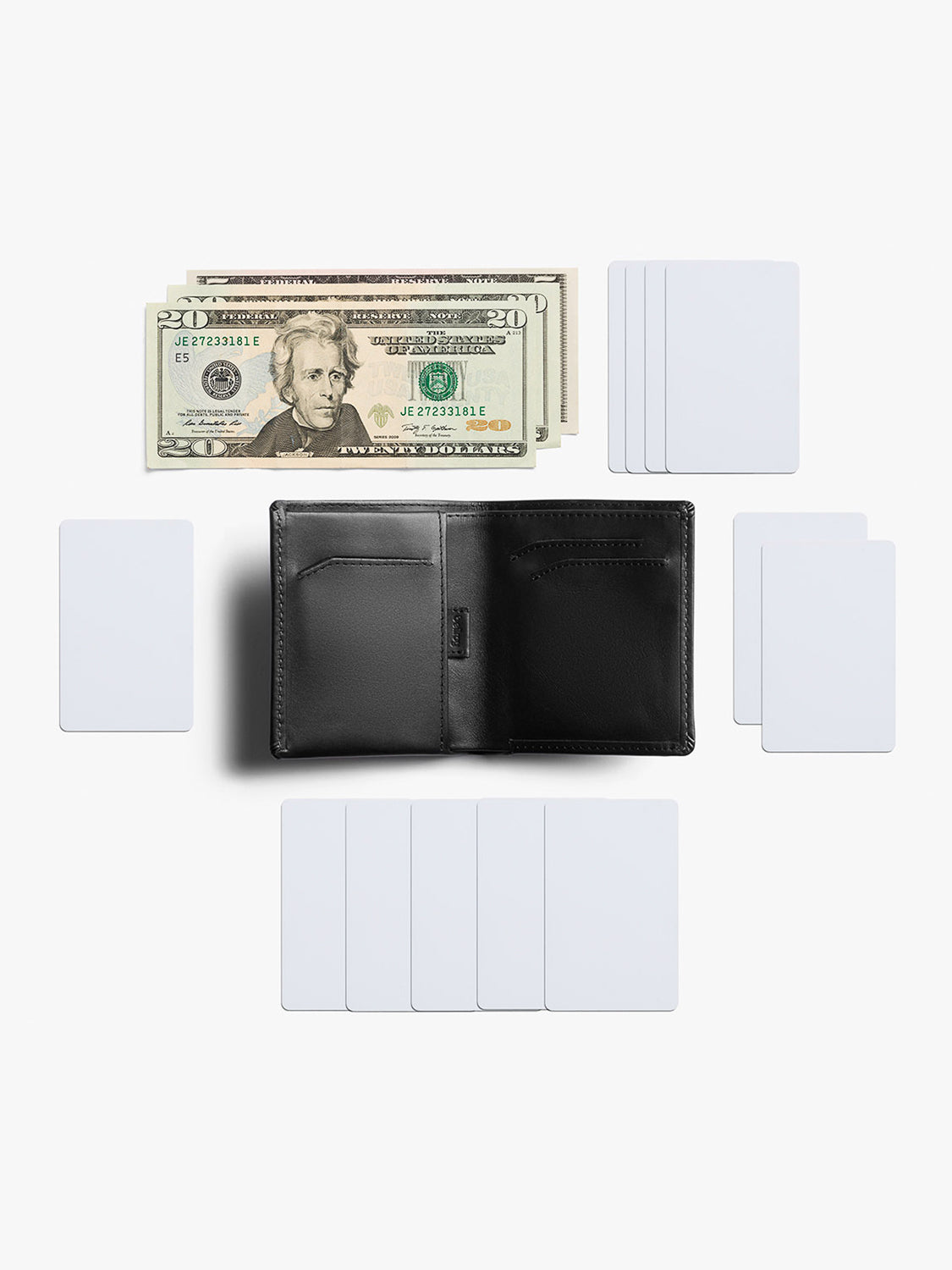 A Bellroy Note Sleeve Wallet in black leather is open and empty, placed on a white background with five stacks of blank white cards and neatly arranged US twenty-dollar bills.