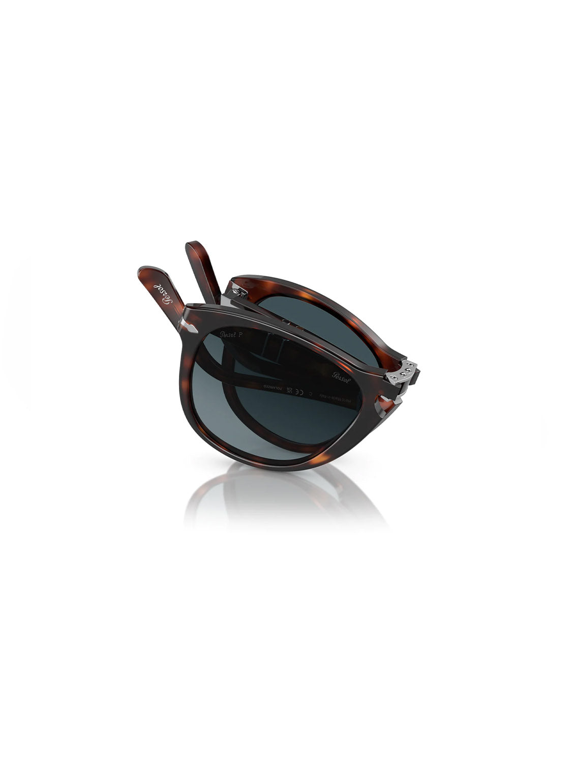 Persol PO714 Polarized Lens sunglasses, featuring a folding tortoiseshell acetate frame and rounded crystal polarized dark lenses, rest on a white surface. The tilted design reveals the sleek hinges.