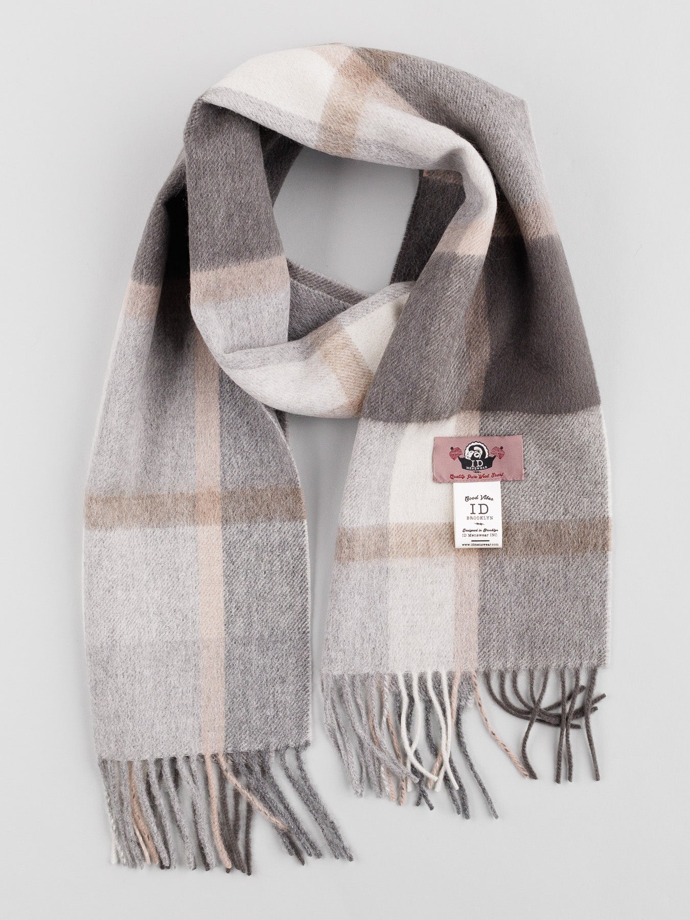 The Wool Timeless Checked Scarf by ID Menswear features a plaid pattern in gray, beige, and white with self-fringed ends. Its folded design showcases brand and material labels against a light gray background.