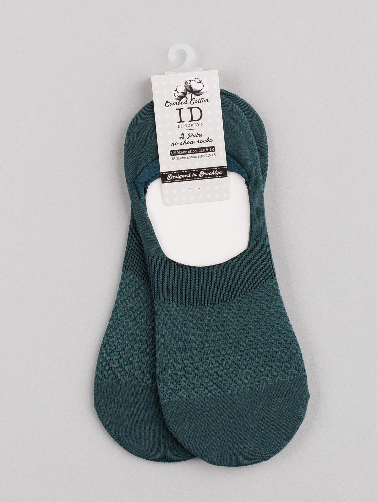 The ID Menswear M1 No Show Socks, made from soft combed cotton, boast a dark teal textured pattern. Ideal for low-cut shoes, they are attractively displayed on a white cardboard hanger with product details on a light gray background.