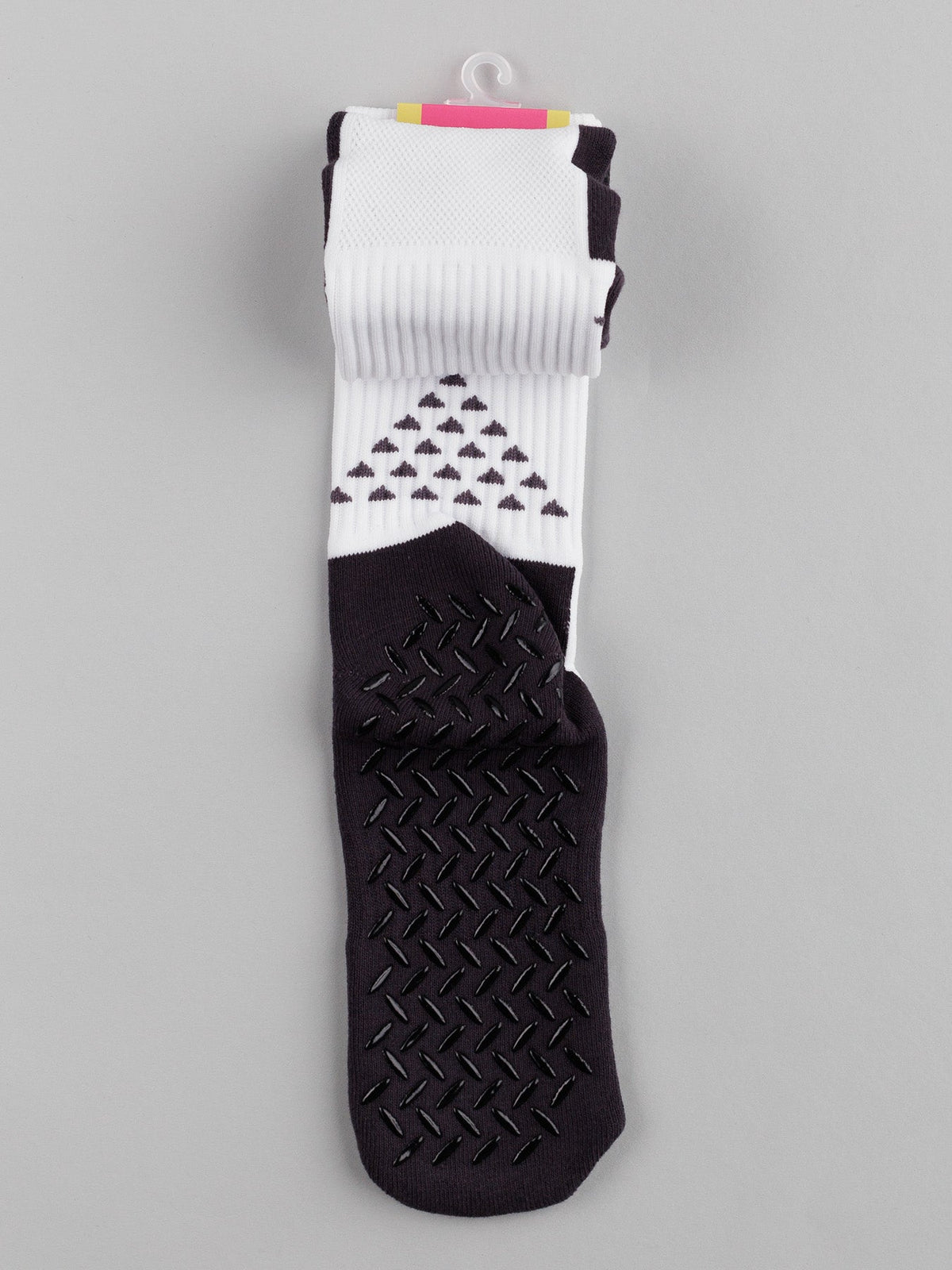 The folded ID Menswear Grip Sports Socks, featuring geometric patterns with black triangles and anti-slip design for improved performance and comfort, are displayed on a gray background.