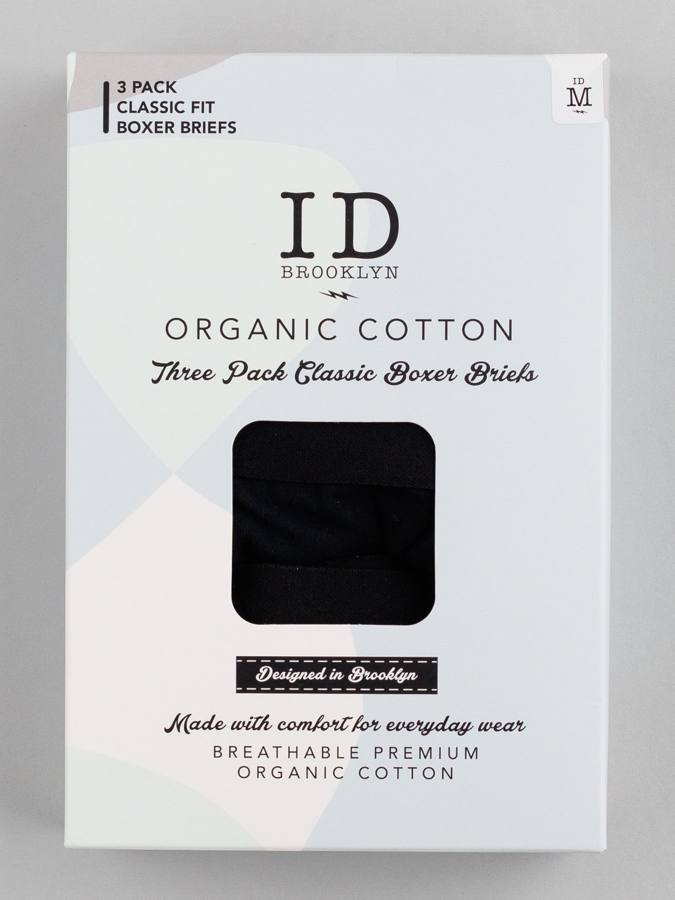 Medium-sized ID Organic Cotton Boxer Briefs 3 Pack by ID Menswear. White packaging with black text reads Three Pack Classic Boxer Briefs and Everyday Essentials designed for comfort and stretch. A small window reveals the black fabric inside.