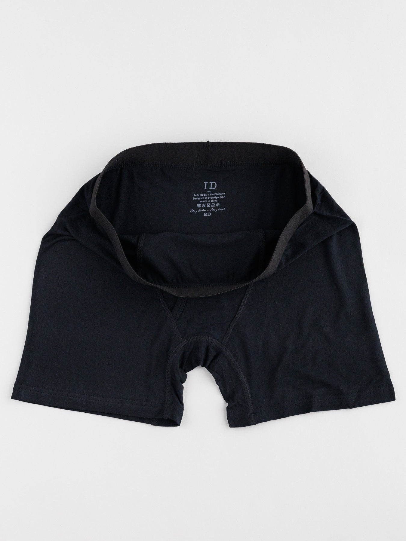 Black mens modal boxer briefs from ID Menswear are laid flat on a white surface, featuring a partially open waistband highlighting the ID Modal Boxer Briefs 3 Pack tag inside. Designed for everyday comfort, they offer just the right amount of stretch.