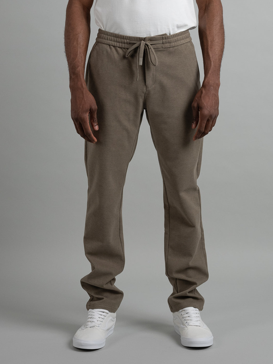 A person wears ID Menswears Brighton Brushed Polyester Rayon Pant in olive green, featuring an elastic waist and drawstring, paired with white sneakers against a plain background. The comfortable fit highlights the lower half of the body with hands relaxed by their sides.