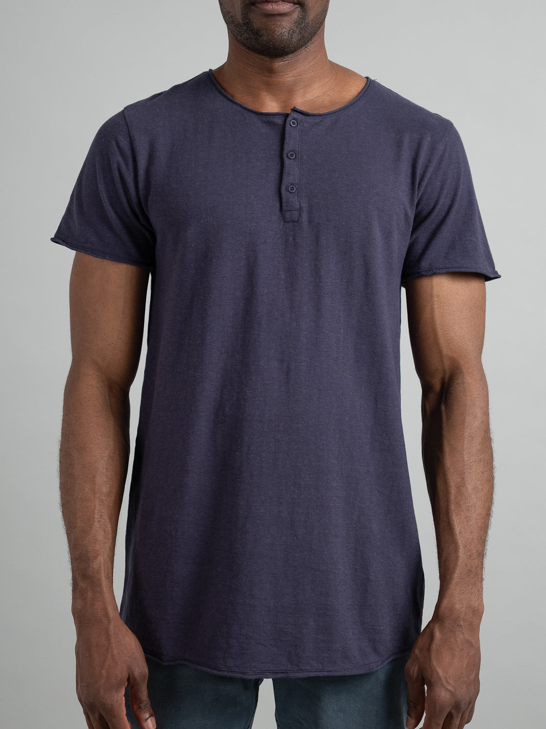 A man wearing the Legend Hemp Cotton Rolled Neck Henley by ID Menswear, made from organic cotton, stands against a gray background. His hands are relaxed at his sides as he faces forward.