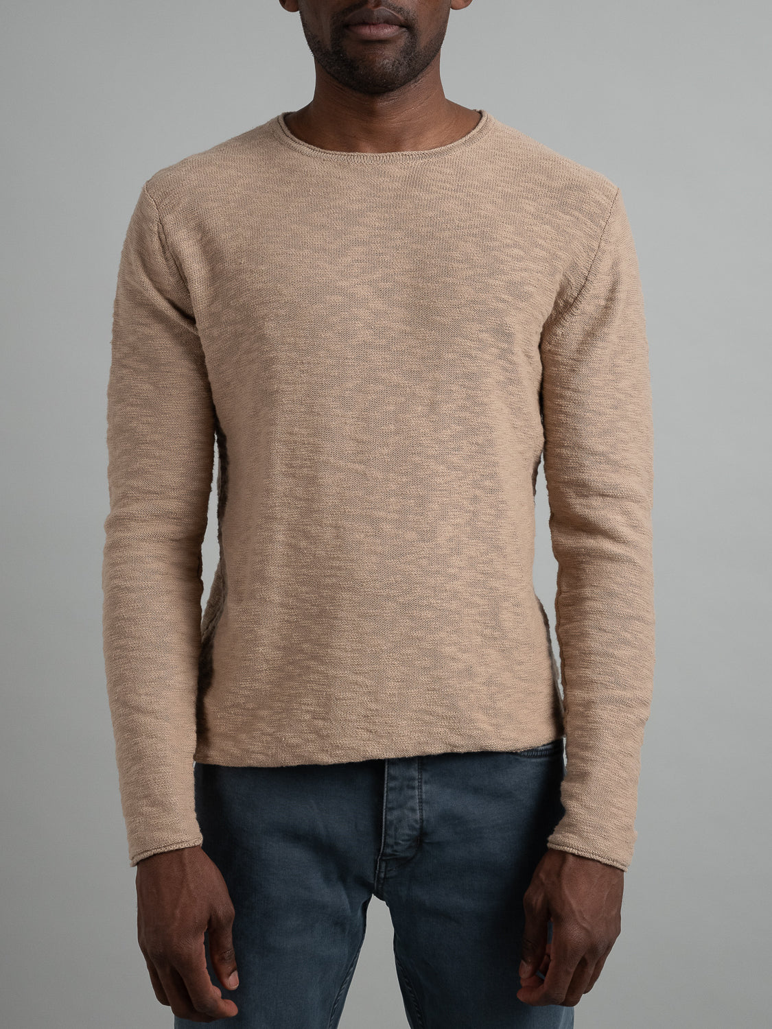 A person stands against a gray backdrop in an ID Menswear Havana Slub Yarn Sweater Tee, showcasing its premium textured fabric, with arms relaxed at their sides. Theyre also wearing dark gray pants, perfectly capturing a laid-back casual style.